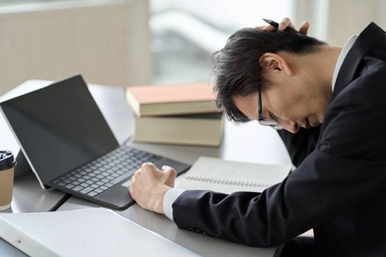 Man stressed at laptop - Misclassification/Overtime